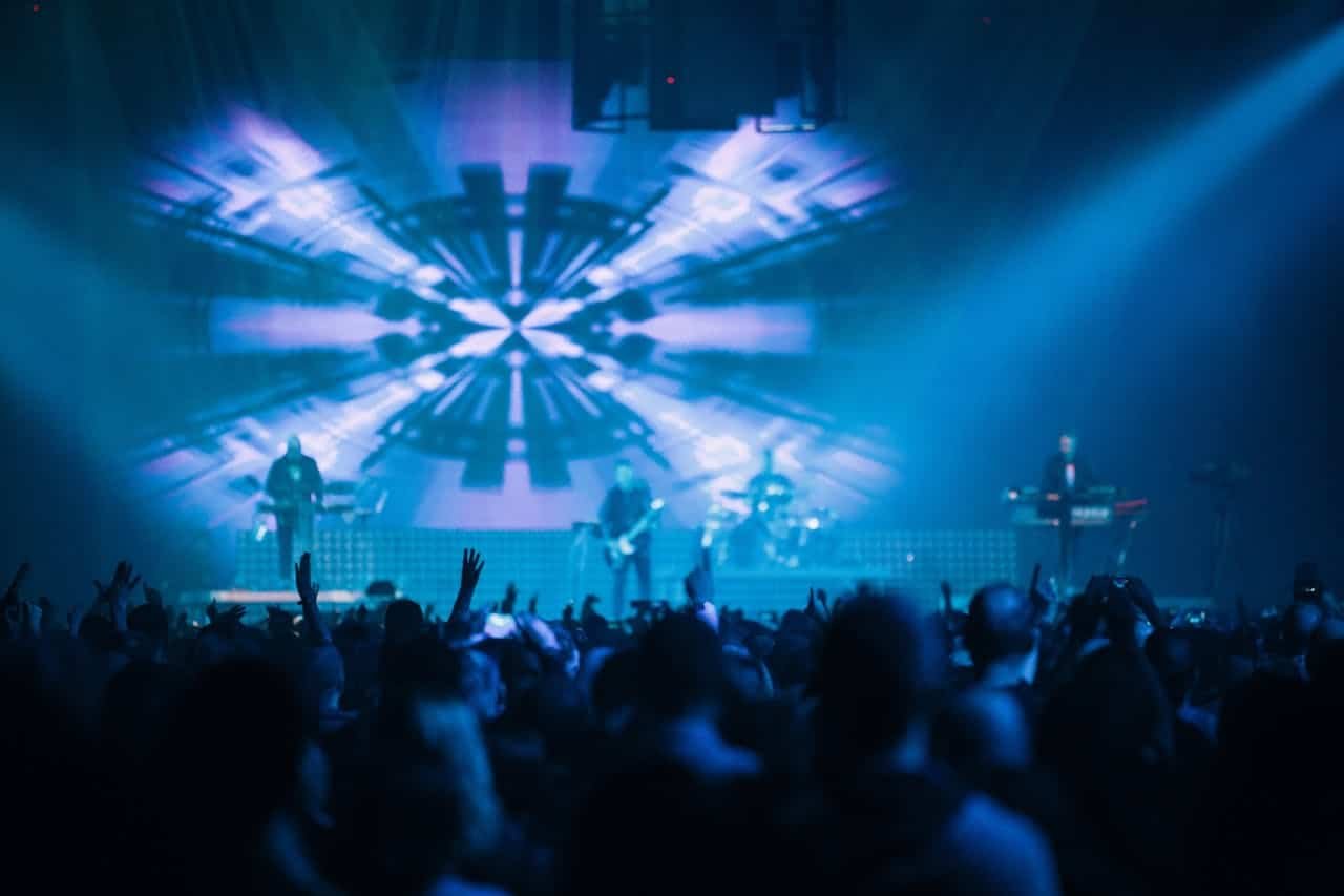 A vibrant scene of a live concert with lights and an enthusiastic crowd.